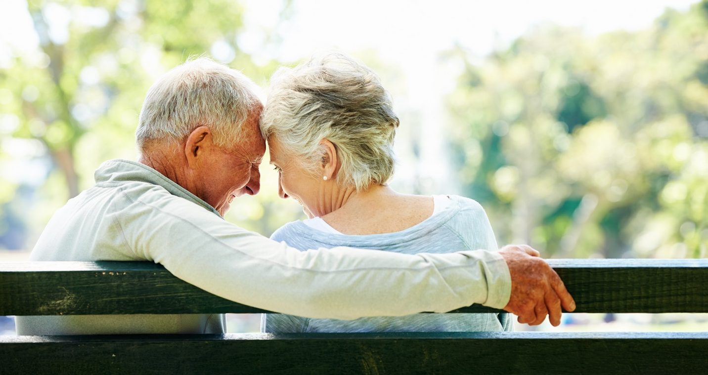 A happy senior couple relaxing together in their local park