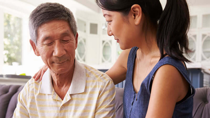 Asian daughter with arm around father