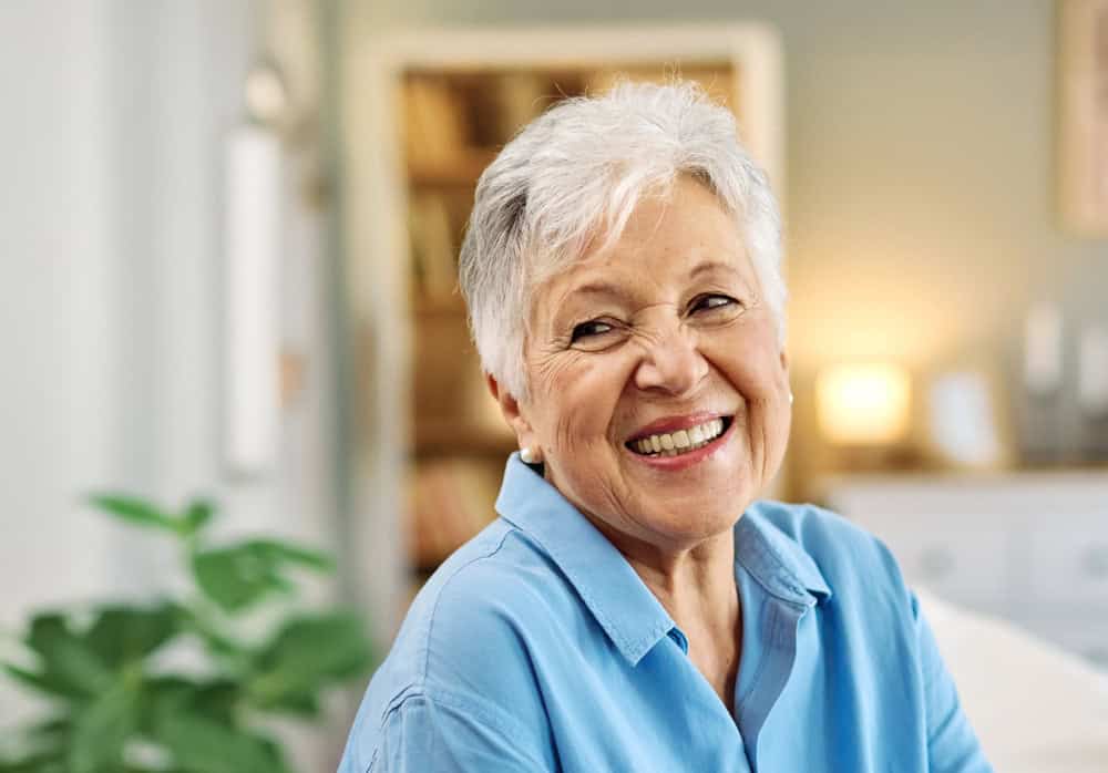 Senior woman with gray hair smiling, representing mental health awareness.