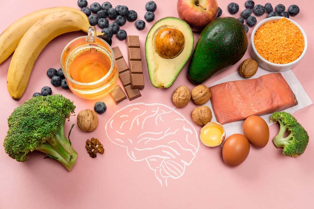 Assorted nutritious foods including fruits, nuts, eggs, and salmon for brain health.