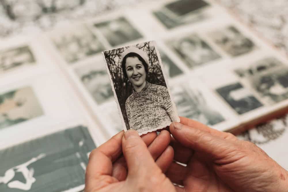 Senior woman holding a black-and-white photo, reflecting on loved ones' mental health.
