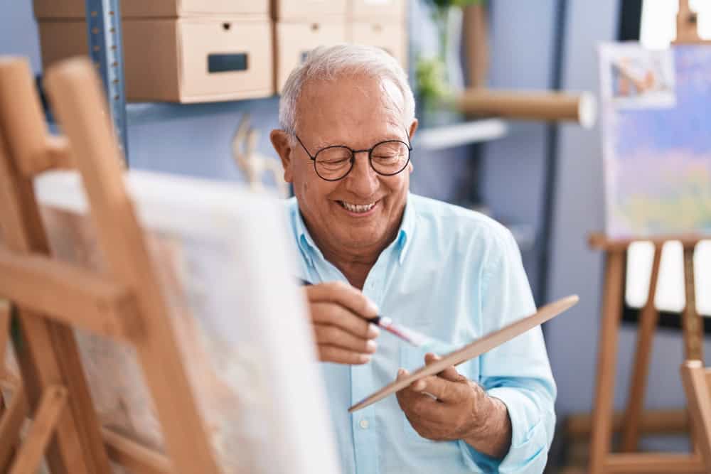 A man seated at an easel painting