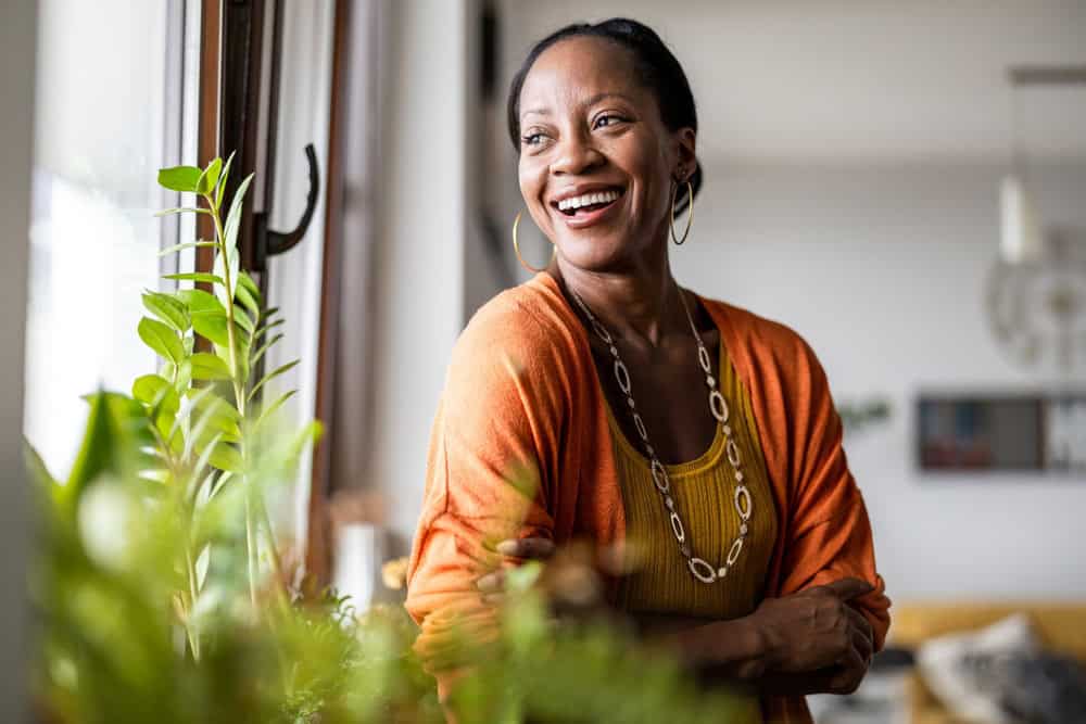 A woman smiling next to a window